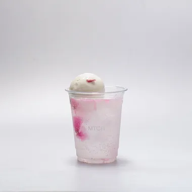 Pink sparkling sakura in a clear cup with a scoop of sakura gelato on the rim